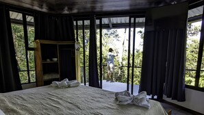 A large bed with a patterned bedspread, a wooden headboard, and a wooden wardrobe. - Quality Cabins Monteverde #4 (Monteverde)