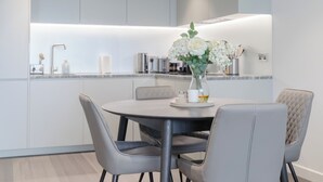 Un'area pranzo moderna con un tavolo rotondo, sedie grigie e un vaso di fiori.