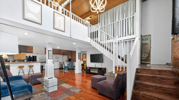 A spacious living area with a wooden staircase, a kitchen, and a dining area. - Stylish Loft with Modern Amenities in Detroit (Detroit)