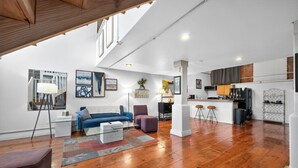 A spacious living area with a blue sofa, a coffee table, and a modern kitchen in the background. - Stylish Loft with Modern Amenities in Detroit (Detroit)