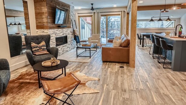A modern living room with a fireplace, leather furniture, and a large window overlooking a snowy landscape.