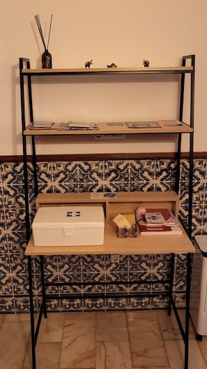 Una estantería metálica de dos niveles, uno con libros y otro con una caja blanca y una etiqueta verde.