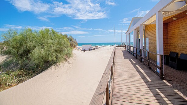 A wooden boardwalk leading to a beach with a clear sky.