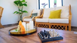 A living room with a chessboard, a glass tray with candles, and a sofa with cushions.