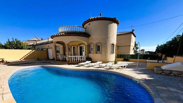 A swimming pool with a curved edge, surrounded by a stone patio. - Villa Jane (Les Tres Cales)