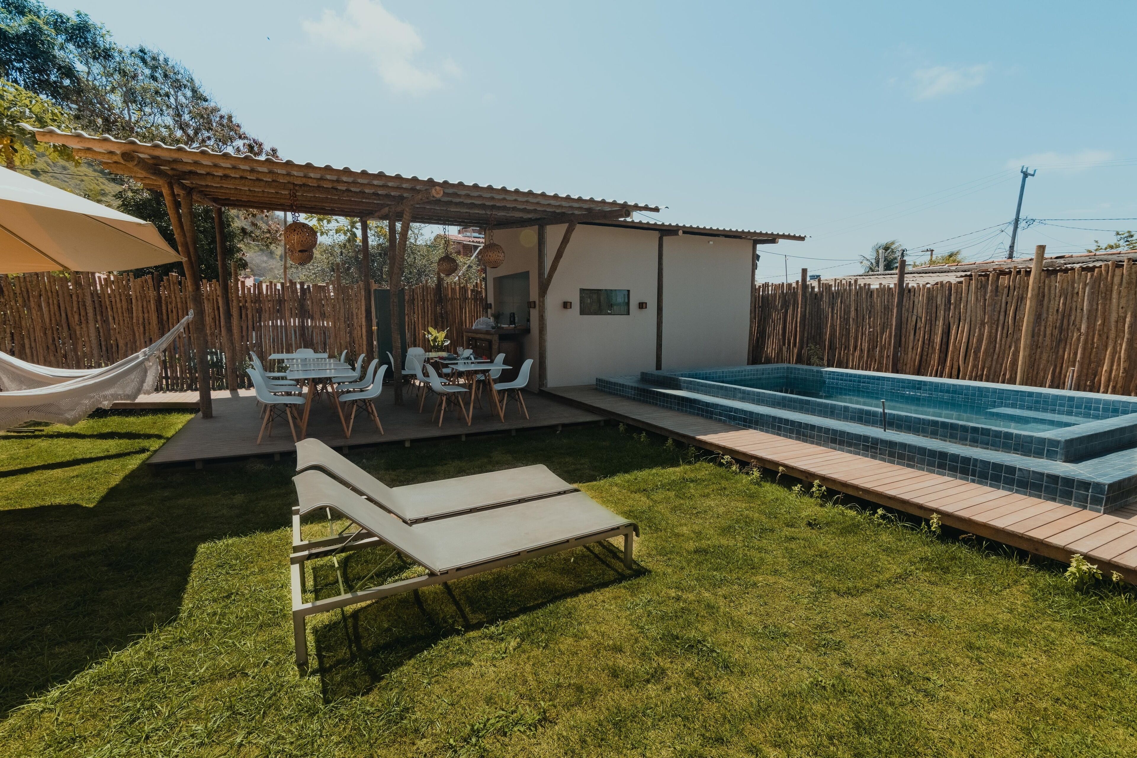 A backyard with a pool, a covered patio, and a hammock.