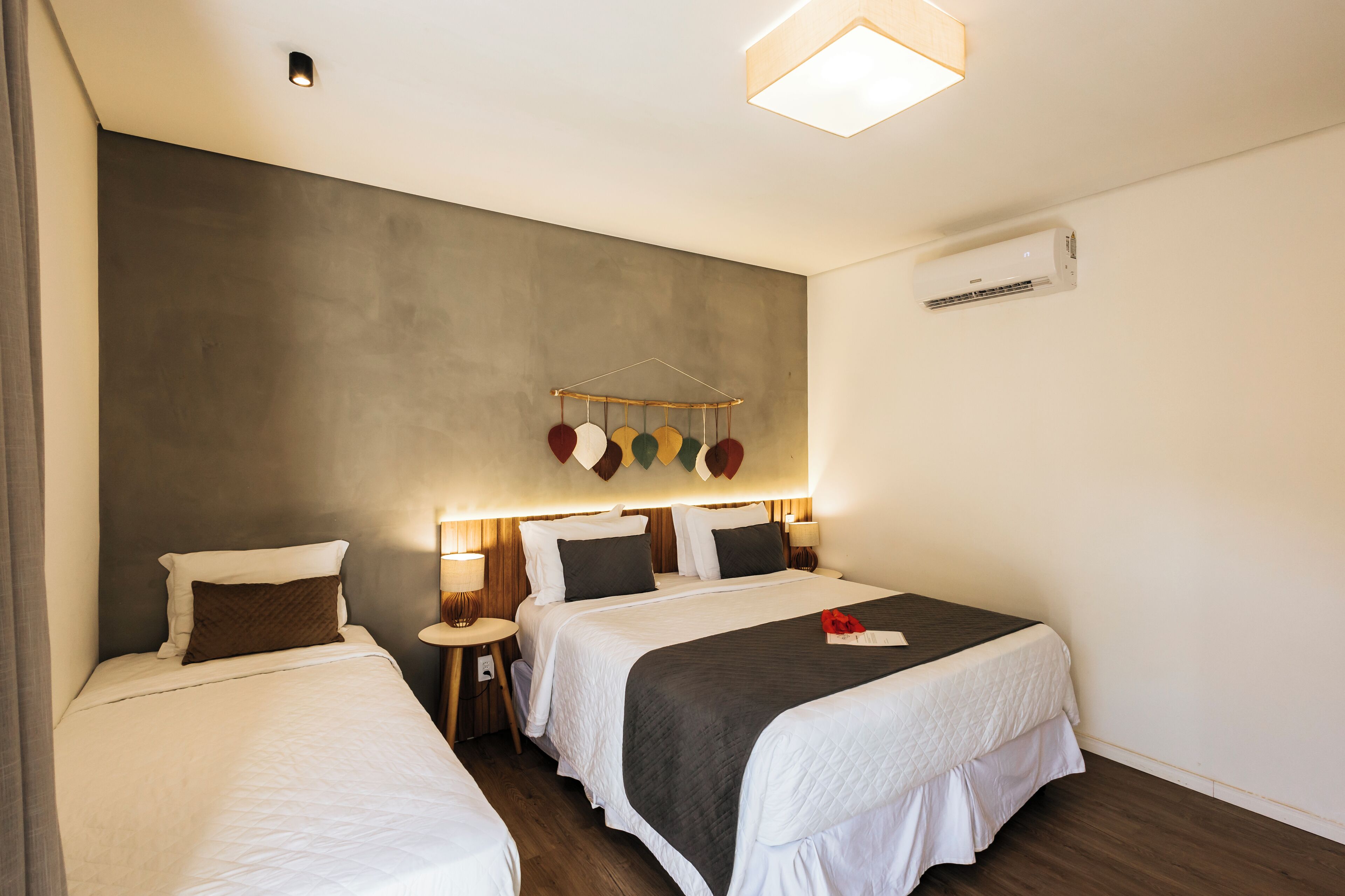 Ein Hotelzimmer mit zwei Betten, einer Hängelampe und einer Klimaanlage.