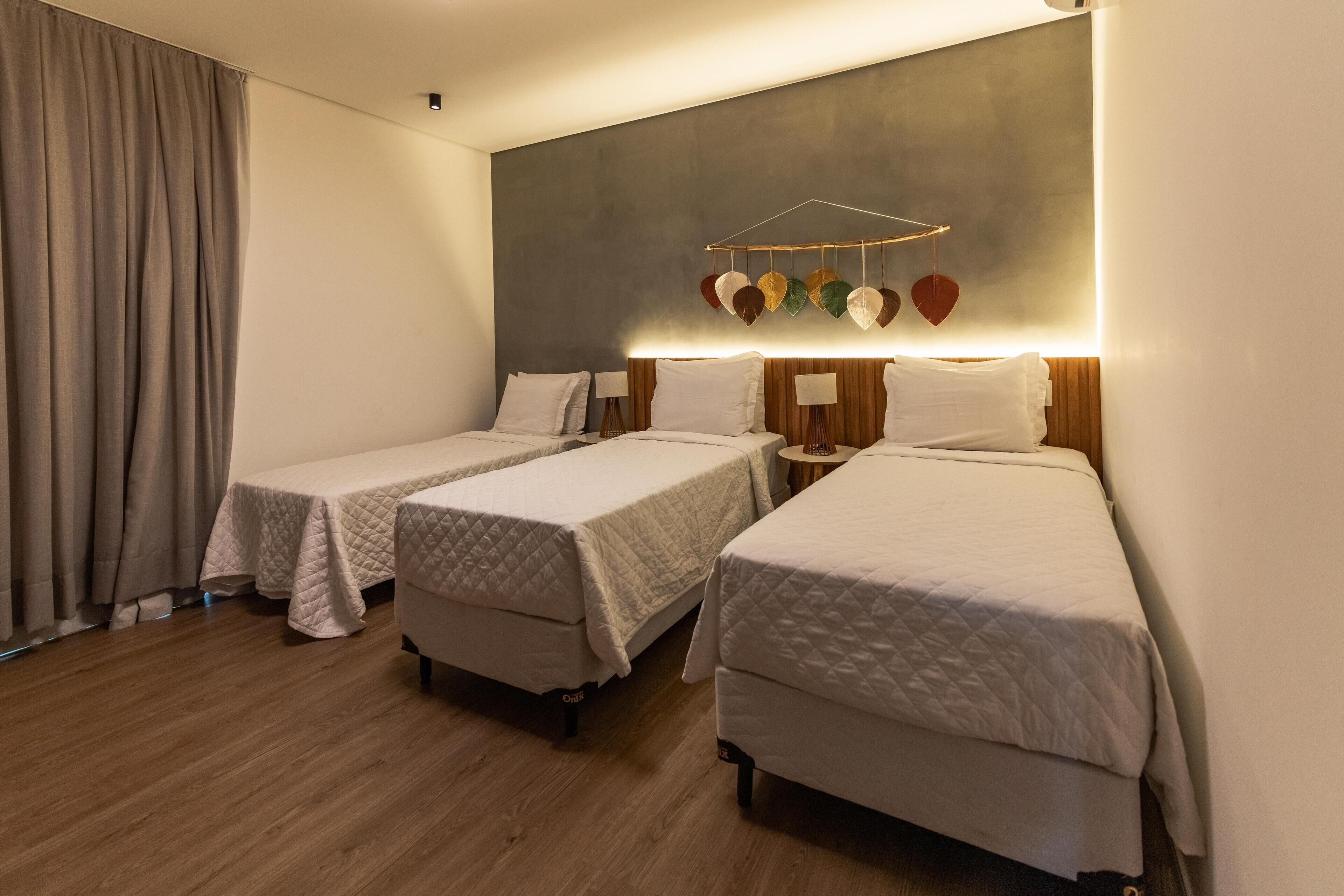 Une chambre d’hôtel avec deux lits simples, un grand luminaire fixé au mur et un plancher en bois.