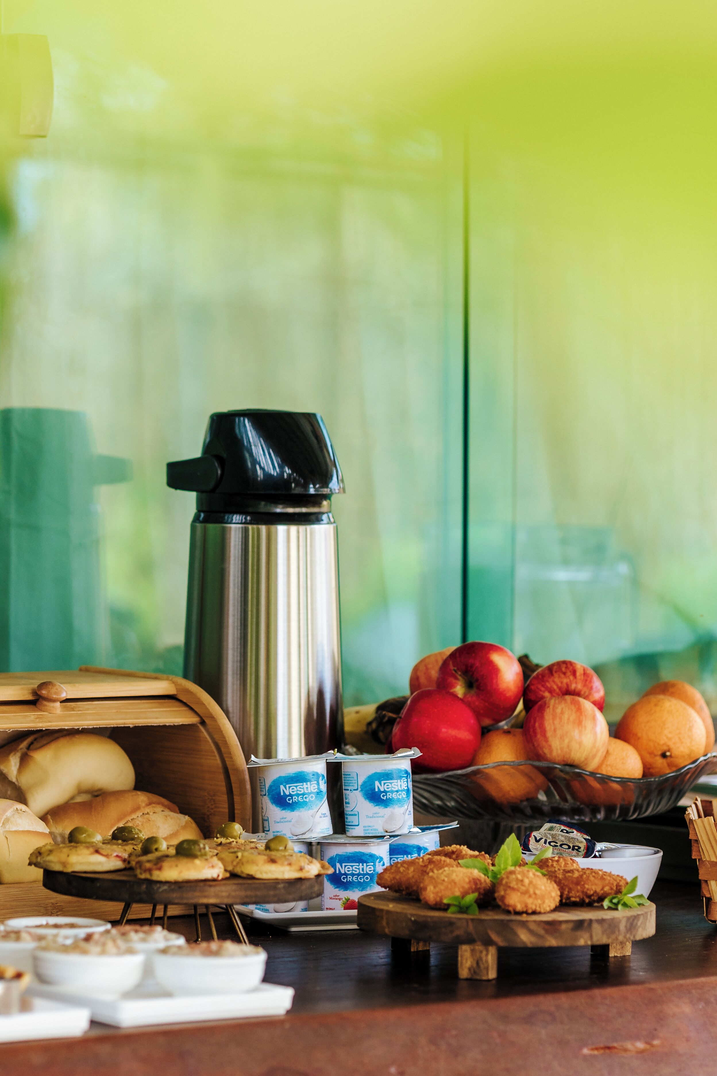 Un bufé de desayuno con diferentes alimentos, una cafetera y un bol de fruta.