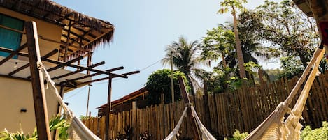 A hammock in a lush garden with a wooden structure overhead.