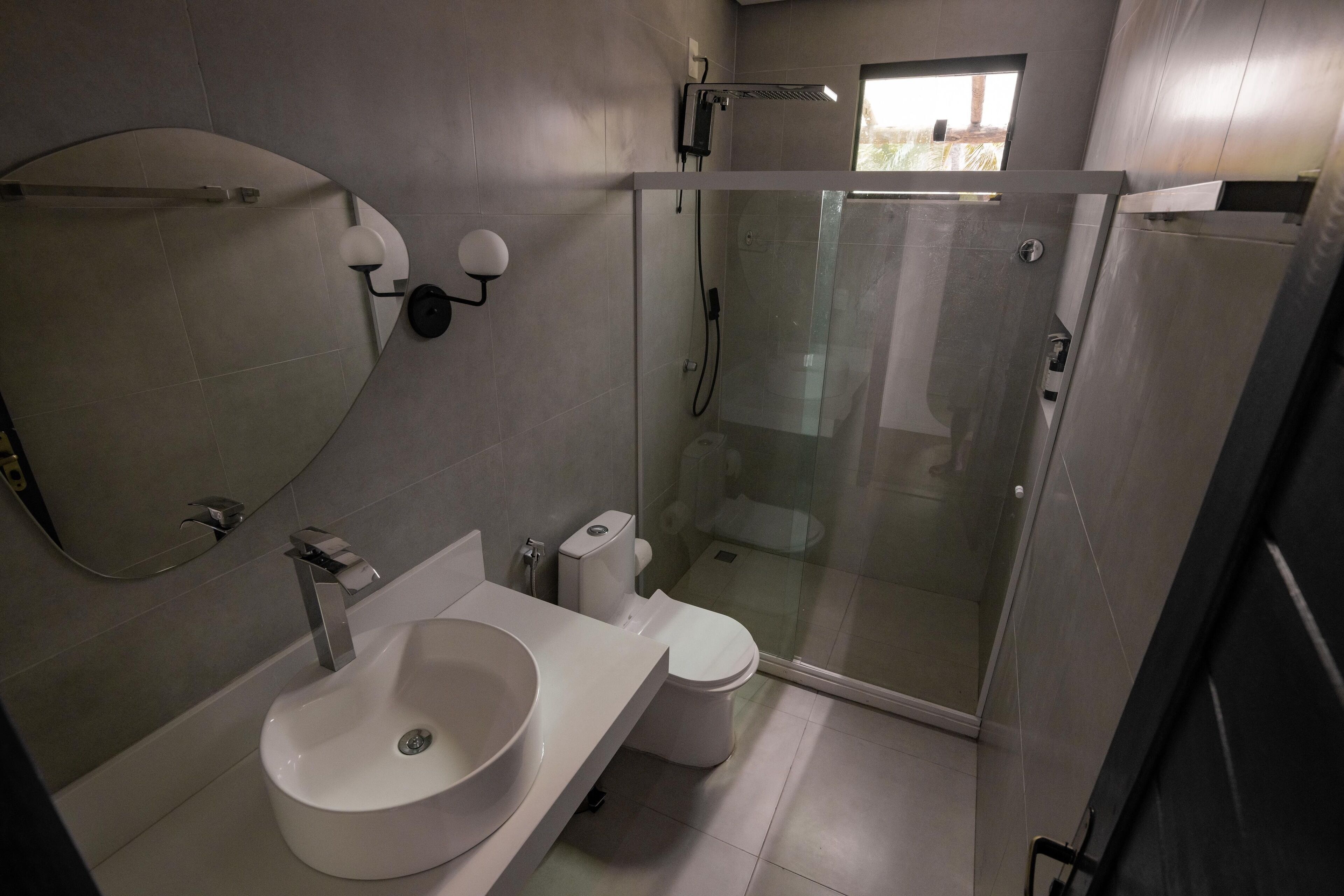 Ein modernes Badezimmer mit einer Duschkabine, einem weißen Waschbecken und einer Toilette.
