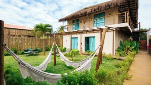 A two-story building with a thatched roof, a hammock, and a wooden deck. - POUSADA AMAR NORONHA (Fernando de Noronha)