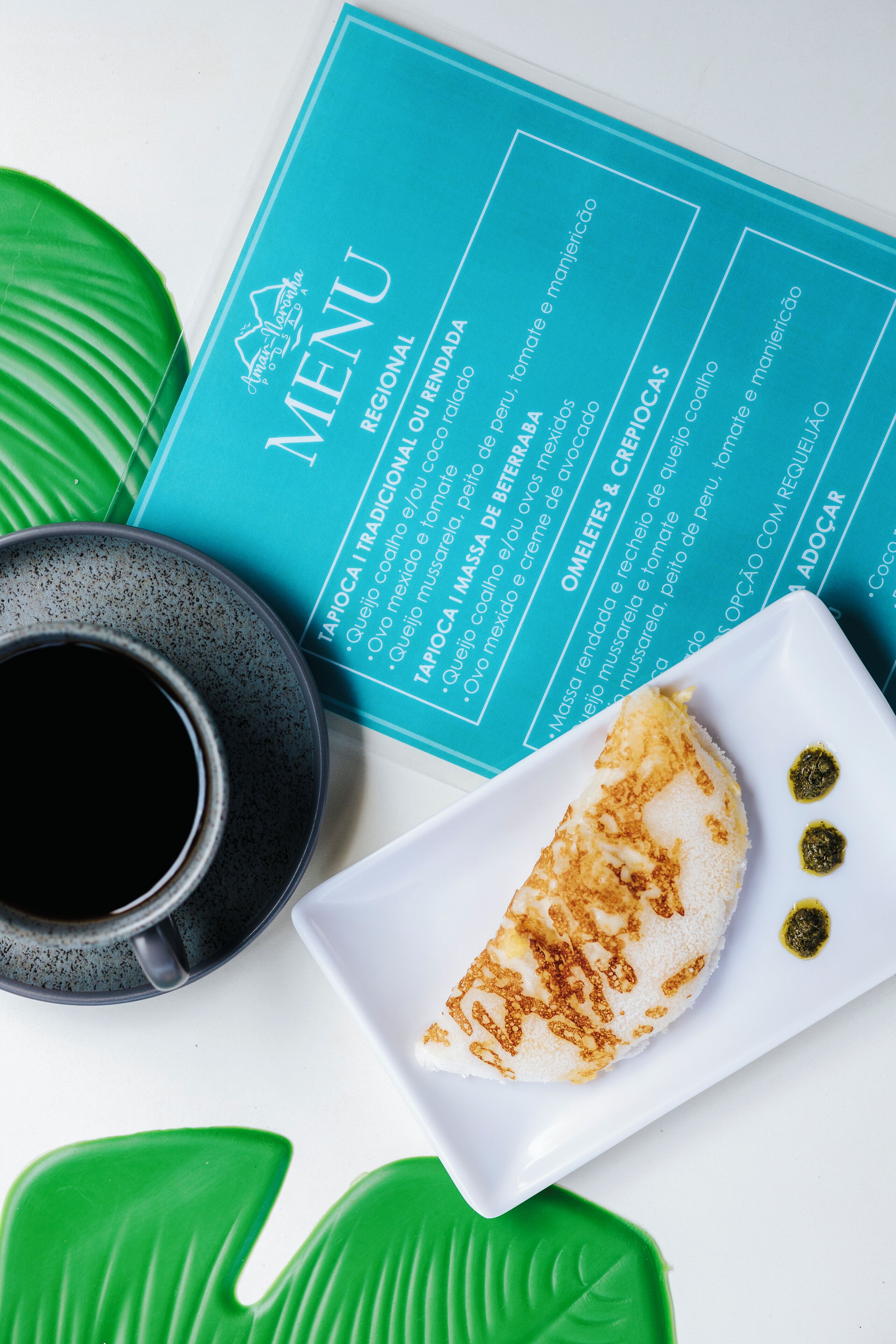 A menu with a regional section, a cup of coffee, and a plate with food.