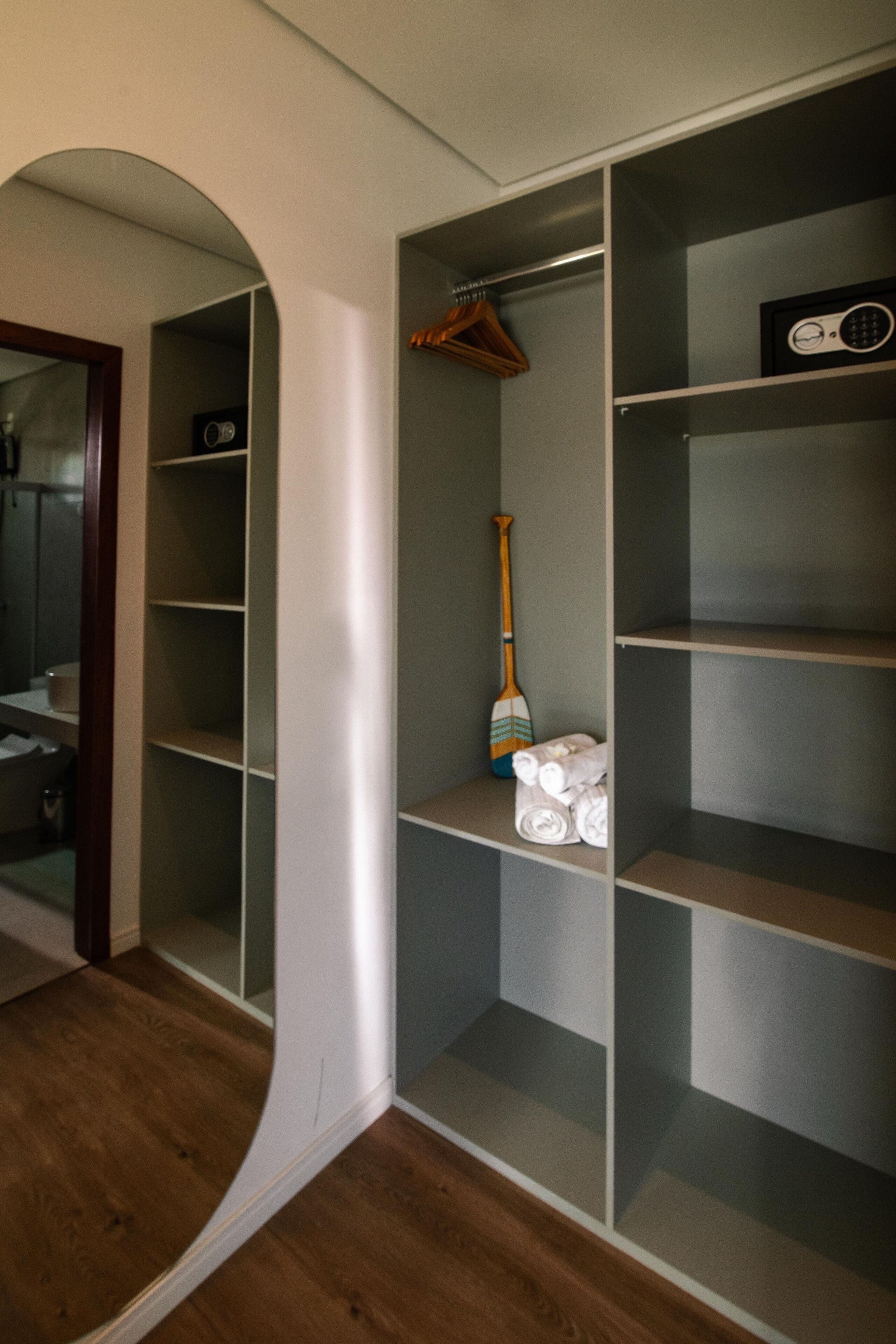 Um closet espaçoso com prateleiras abertas, um cabide de madeira e uma prancha.