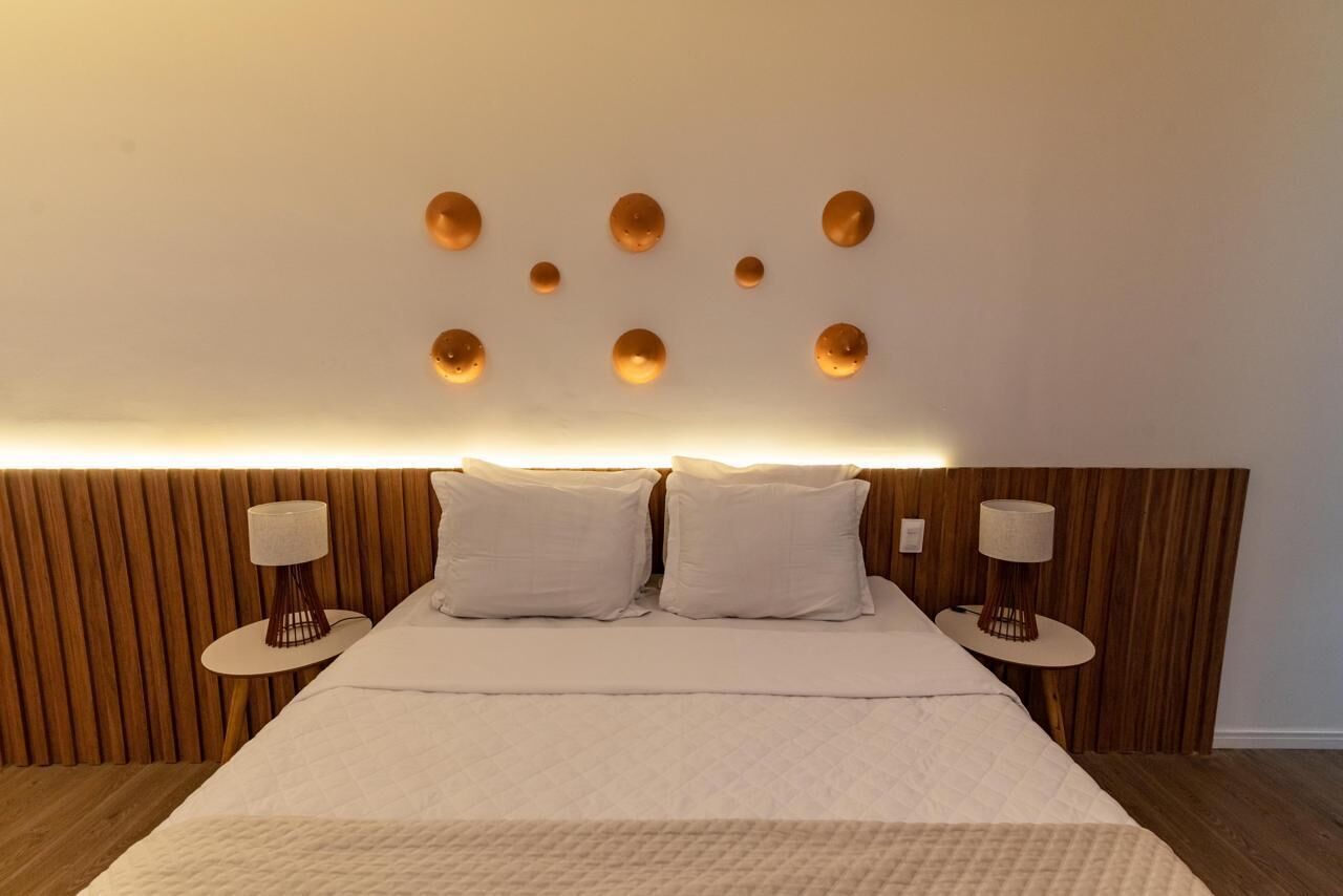 Ein ordentlich eingerichtetes Schlafzimmer mit einem großen Bett, zwei Nachttischen und einer Wandleuchte.