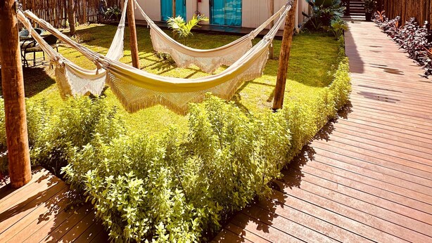 A house with a thatched roof, a wooden deck, and a hammock in the garden. - POUSADA AMAR NORONHA (Fernando de Noronha)