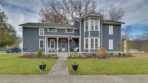 A two-story house with a front porch, a flag, and a mailbox.