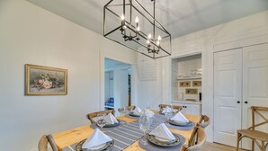 A dining room with a wooden table set for six, surrounded by chairs.
