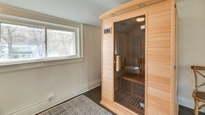 A sauna room with a wooden door, a control panel, and a glass door.