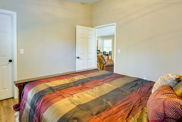 A bedroom with a large bed, a chair, and a door leading to another room.