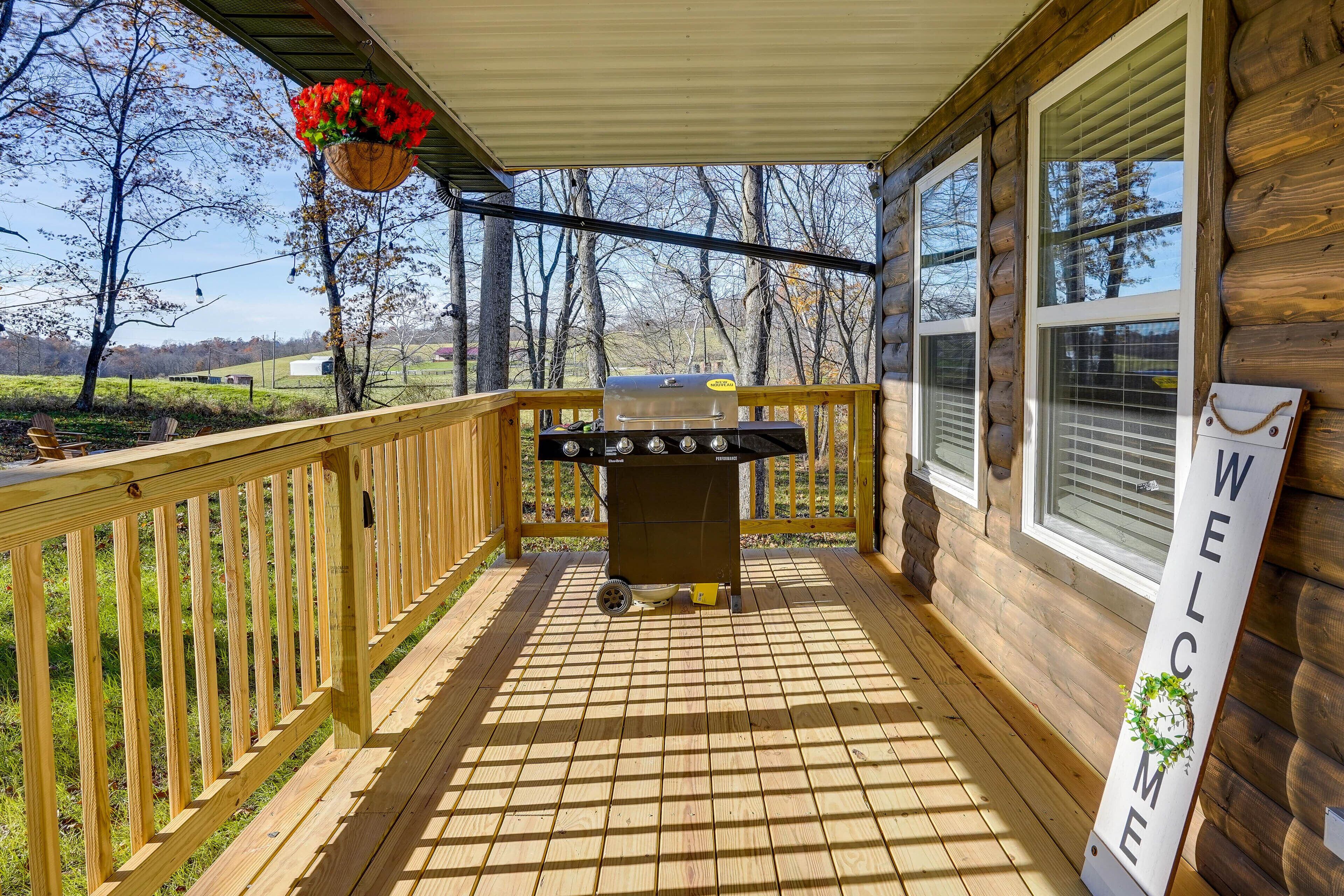 A wooden deck with a barbecue grill, a welcome sign, and a hanging flower basket.