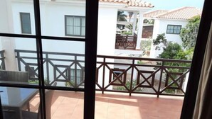 Ein Zimmer mit einer Schiebetür und Zugang zu einer Außenpatio-Terrasse mit Fliesenboden und Holzgeländer.
