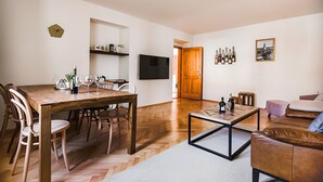 Un salon moderne avec une table à manger en bois, un canapé en cuir et un téléviseur à écran plat fixé au mur.