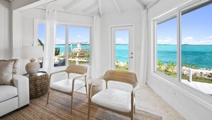 A spacious room with large windows offering a view of the ocean and a deck area. - Waterfront Georgetown home, 8ppl,Chef, Boat Tour (Exuma)