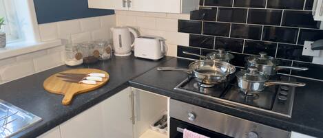 A modern kitchen with white cabinets, a black countertop, a stove, and an oven.