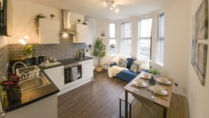Een moderne keuken met een centraal eiland, inbouwapparatuur en een eethoek met een tafel gedekt voor vier personen.