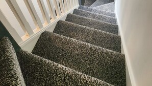 Una scala con gradini rivestiti di moquette che conduce a un pianerottolo con una finestra.