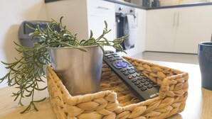 Un cesto intrecciato con un telecomando e una pianta in vaso su un tavolo di legno.