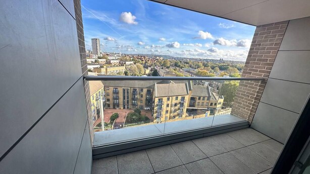 Un balcón con vistas a un paisaje urbano, que muestra edificios modernos y un cielo despejado.