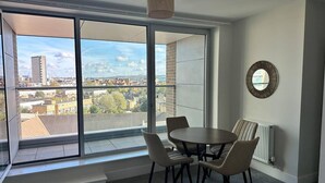 Una habitación moderna con un ventanal grande, una mesa redonda con sillas y un radiador.