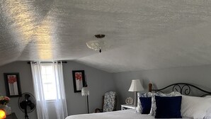 A bedroom with a large bed, a bedside table, a chair, a floor lamp, and a window with curtains. - The Blue Door Cottage  (Dundee)