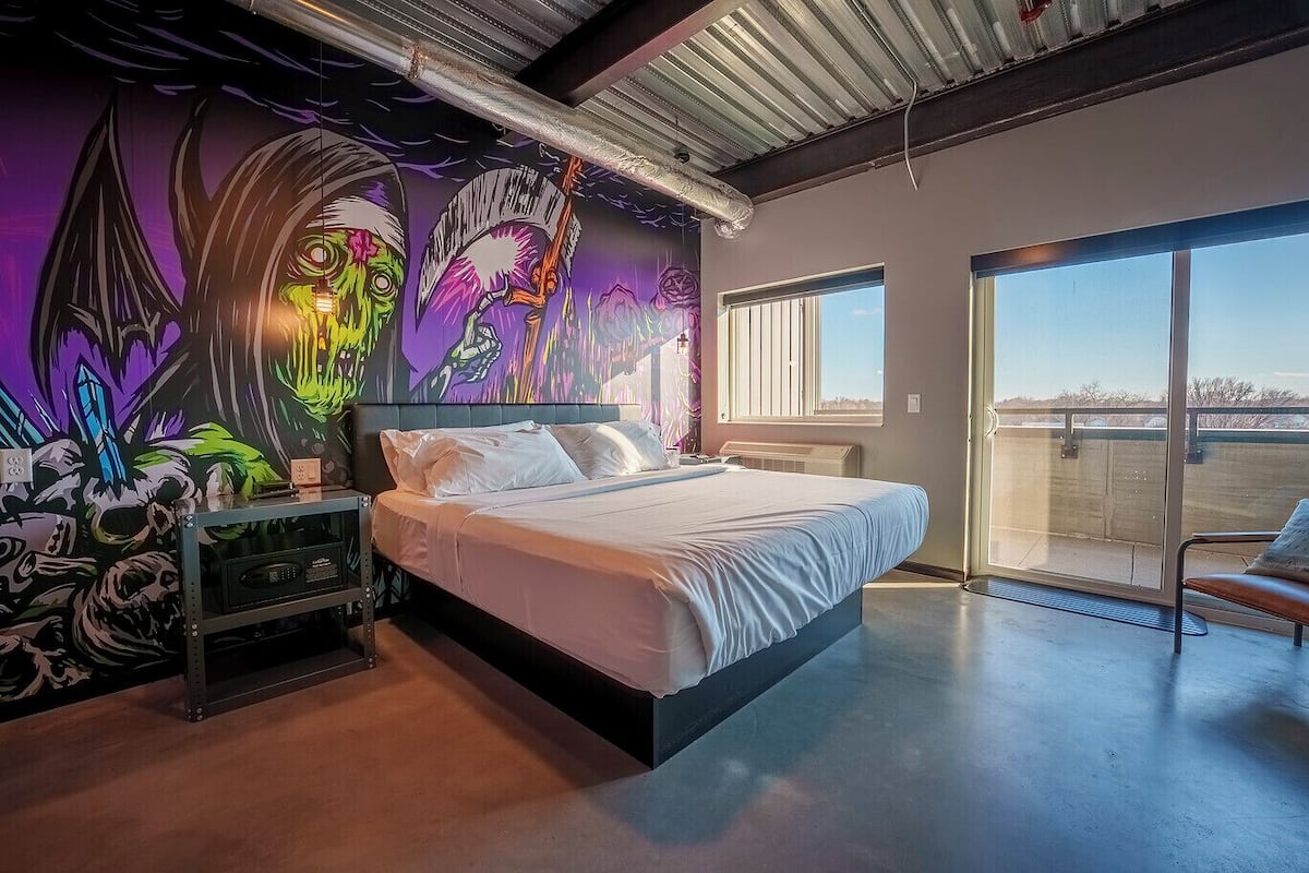 Quarto moderno com cama grande, um mural na parede e varanda com vista.