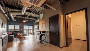 Una cocina moderna con barra, comedor con vistas y una puerta grande de color oscuro.