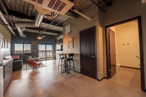 A modern kitchen with a bar area, a dining space with a view, and a large dark door.
