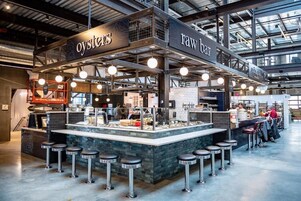 A bar area with stools and a counter labeled "Oysters" and "Raw Bar".