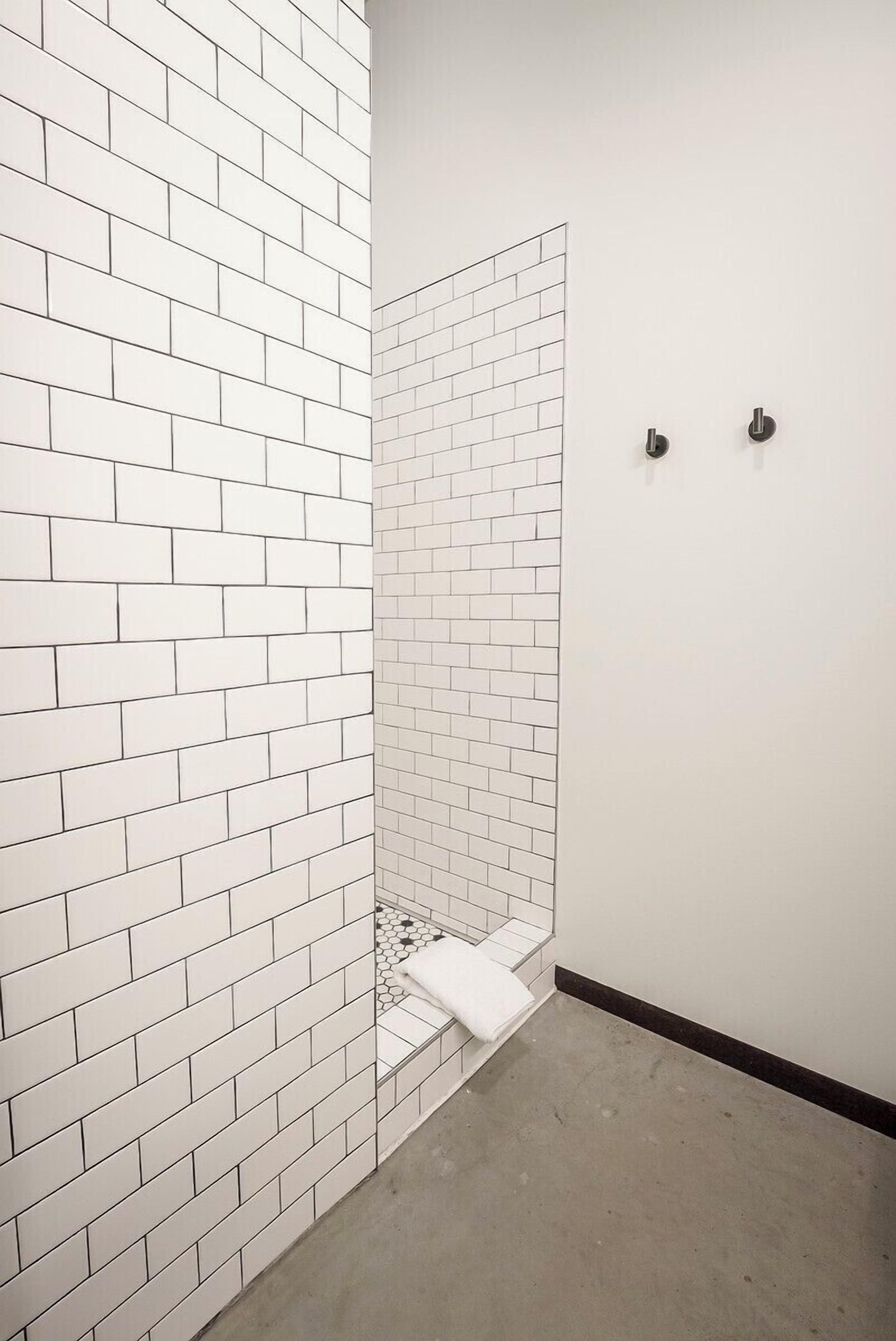 Baño con paredes de ladrillo blanco, zona de ducha y un inodoro.