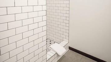Baño con paredes de ladrillo blanco, zona de ducha y un inodoro.