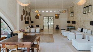 Un amplio salón con una mesa de comedor de madera, sofás blancos y una pared de piedra.