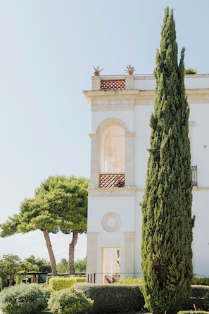 A white building with a central arched window and a tall, narrow tree in front. - MASTROPA' EXCLUSIVE RESORT (Massafra)
