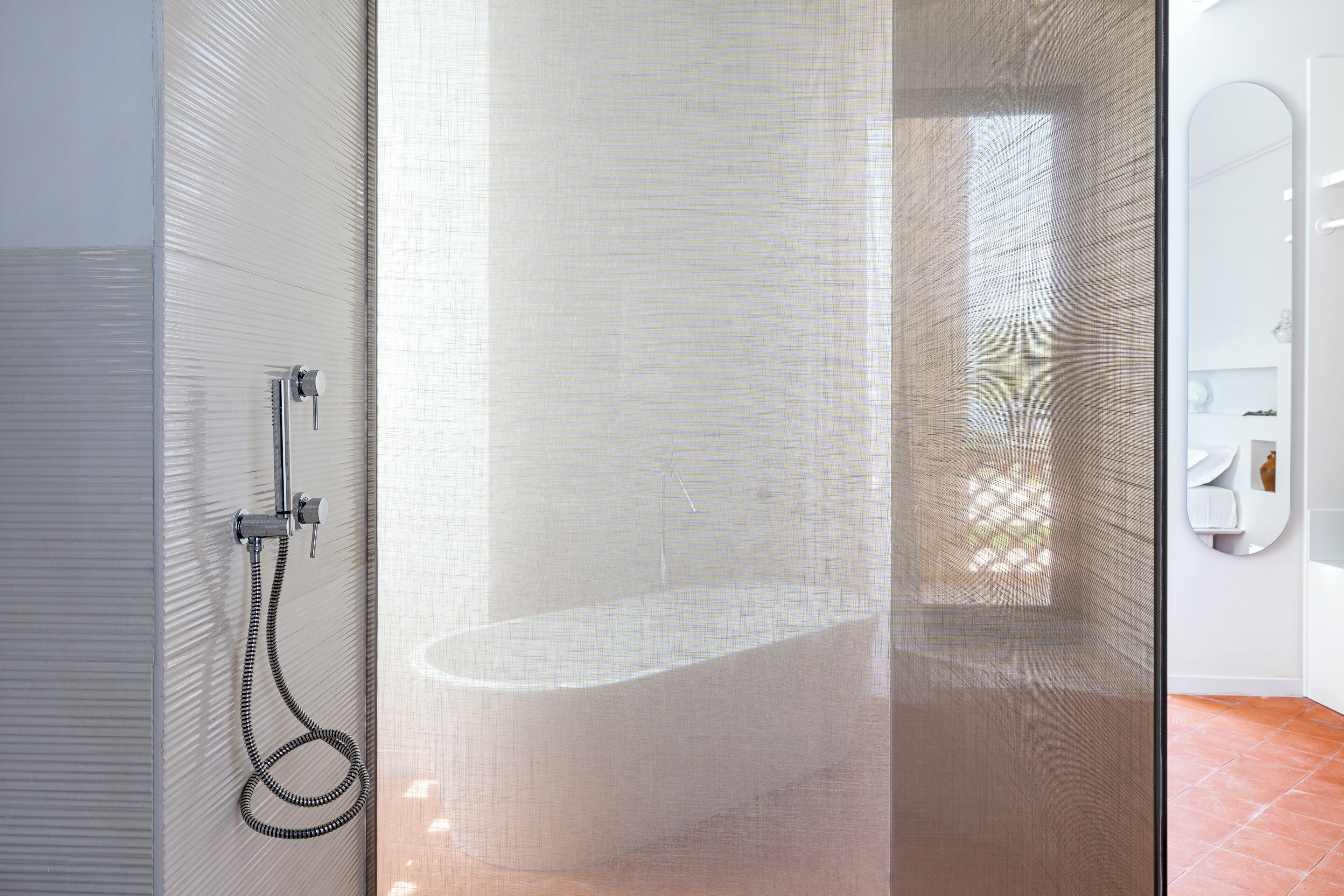 A modern bathroom with a glass shower enclosure, a freestanding bathtub, and a white vanity with a mirror.