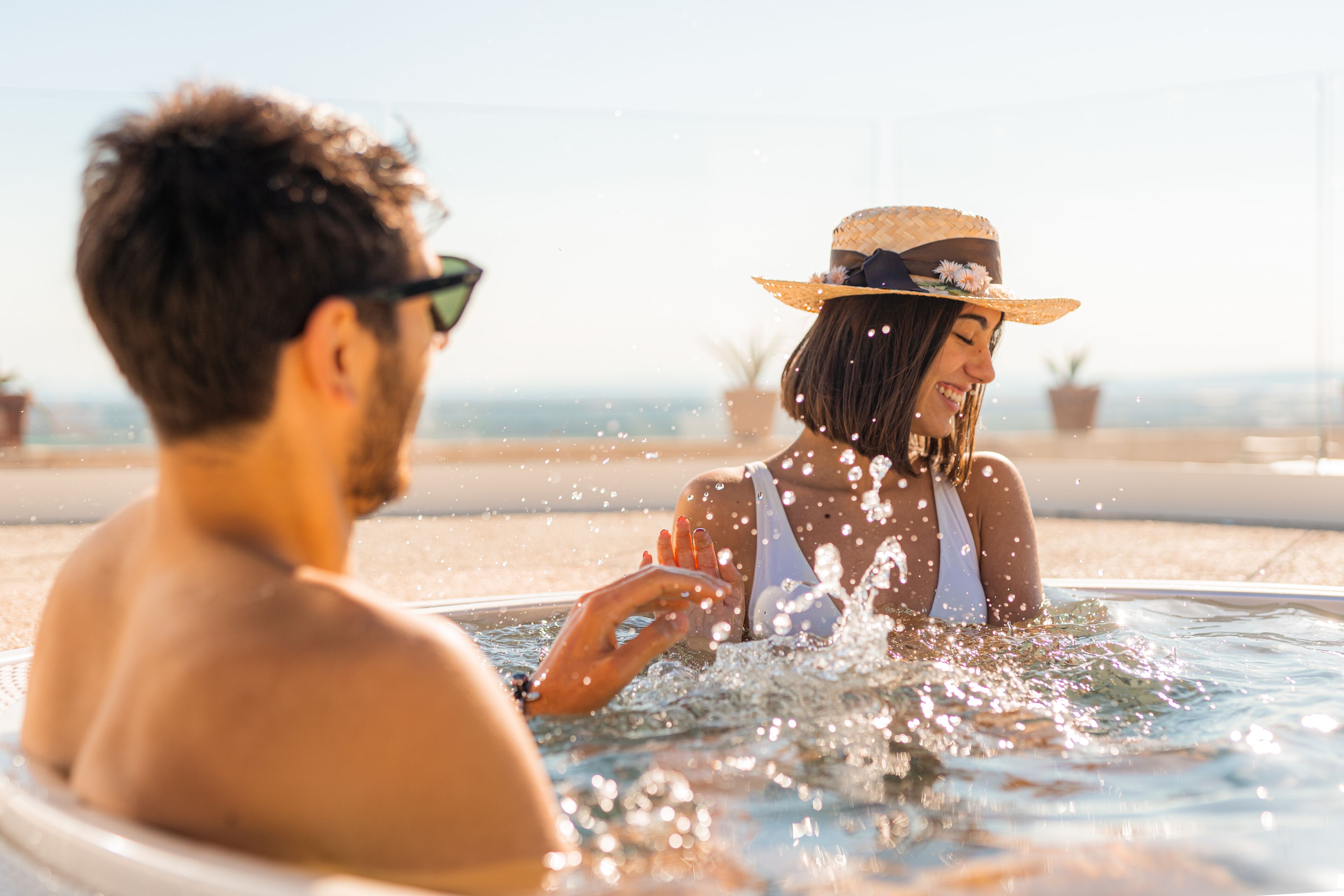 Una pareja en un jacuzzi con vistas a la playa.