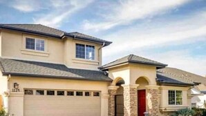 A two-story house with a garage, a stone entrance, and a clear sky.
