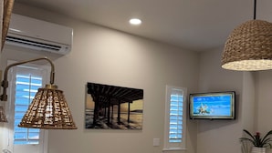 A bedroom with a bed, a television, and a wall-mounted air conditioner.