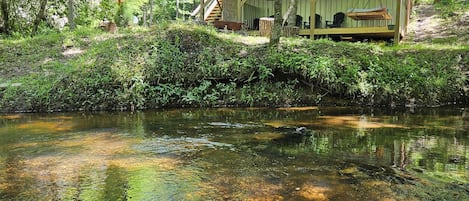 A wooden cabin with a deck and a river in front.