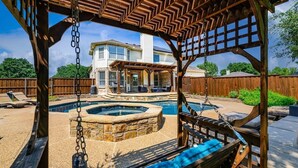 A backyard with a hot tub, a swing, and a covered patio area. - Secluded Luxe Home | Private Pool & Grill (Allen)