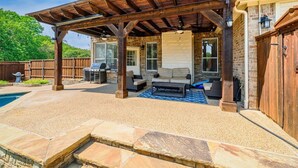 A covered patio area with outdoor seating, a barbecue grill, and a pool. - Secluded Luxe Home | Private Pool & Grill (Allen)
